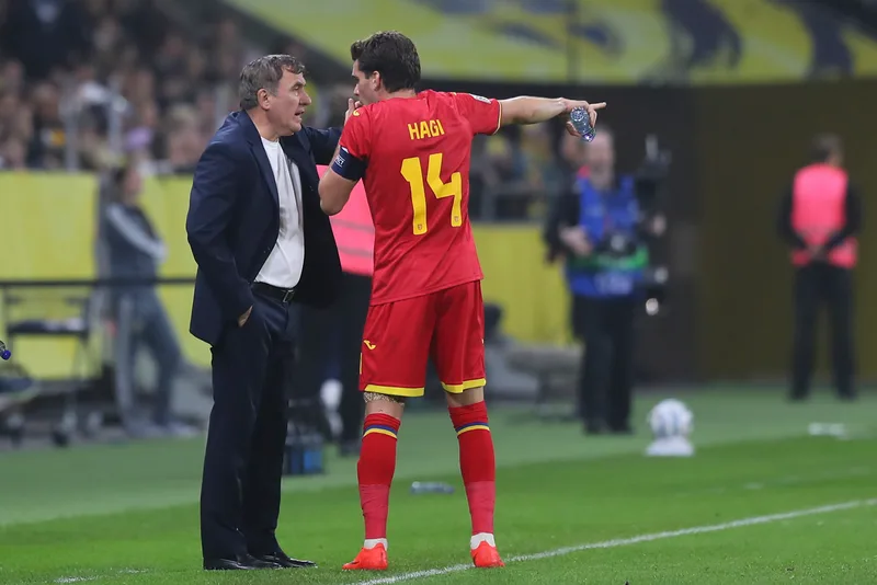 Bărbat în costum discutând cu jucătorul cu numărul 14 și numele Hagi pe tricou, la meciul Suedia-România