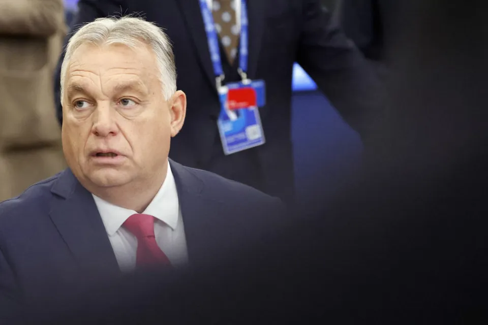Viktor Orbán, cu părul alb, în costum și cravată roșie, privind într-o parte