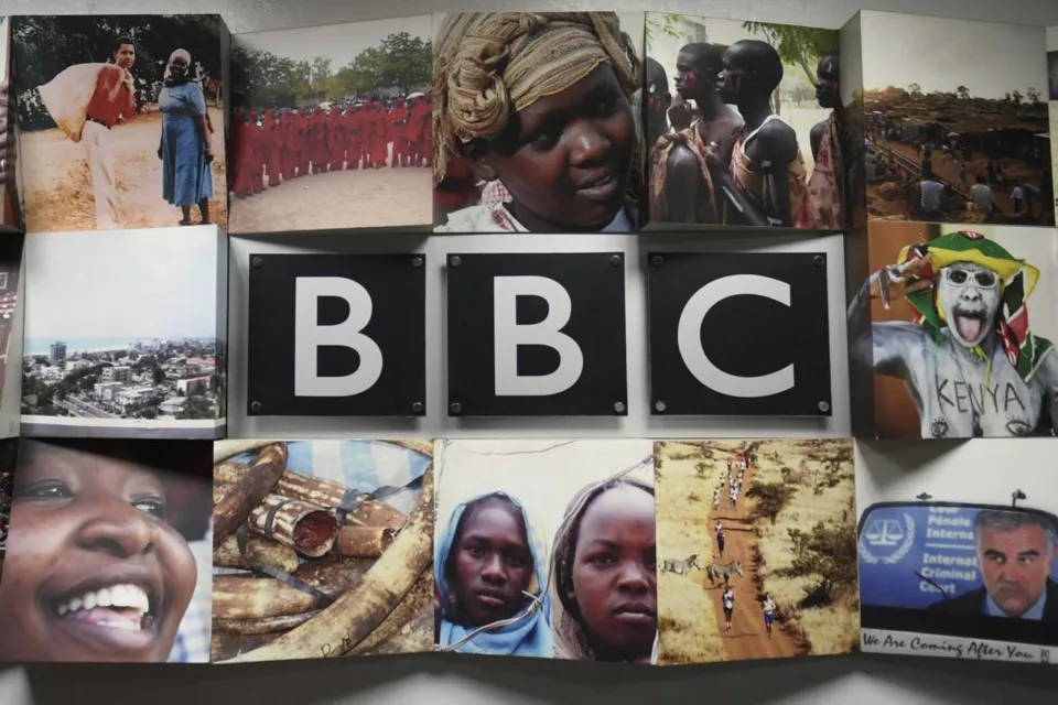 Sigla BBC pe un panou acoperit cu fotografii de oameni și peisaje din Africa