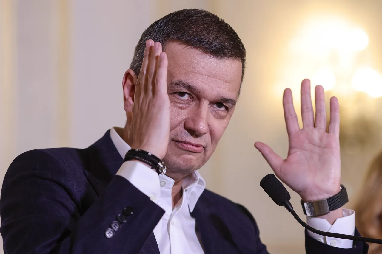 Bărbat în costum, cu o mână la tâmplă și cealaltă ridicată, la un microfon