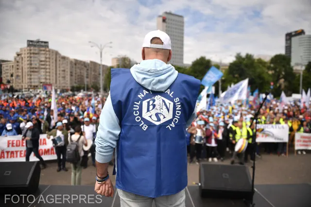 Sindicalist cu vesta Blocului Național Sindical, cu spatele, în fața unei mulțimi de protestatari
