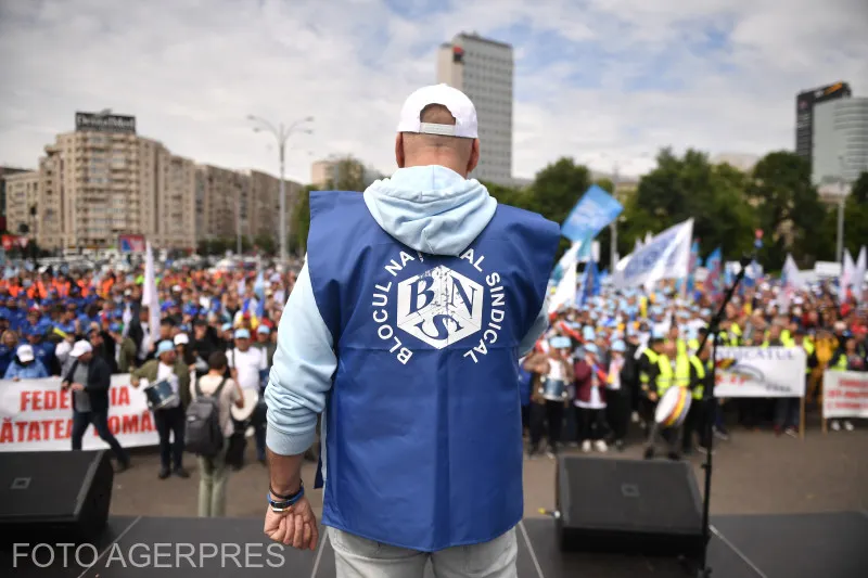Sindicalist cu vesta Blocului Național Sindical, cu spatele, în fața unei mulțimi de protestatari