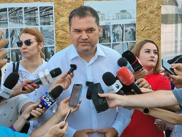 Cseke Attila, în cămașă albă, vorbind presei în fața unor microfoane întinse