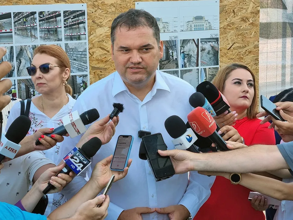 Cseke Attila, în cămașă albă, vorbind presei în fața unor microfoane întinse