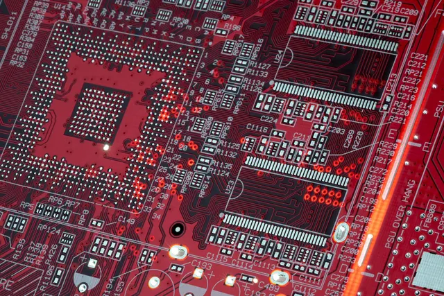 Placă de circuit roșie cu cipuri și trasee, văzută de aproape