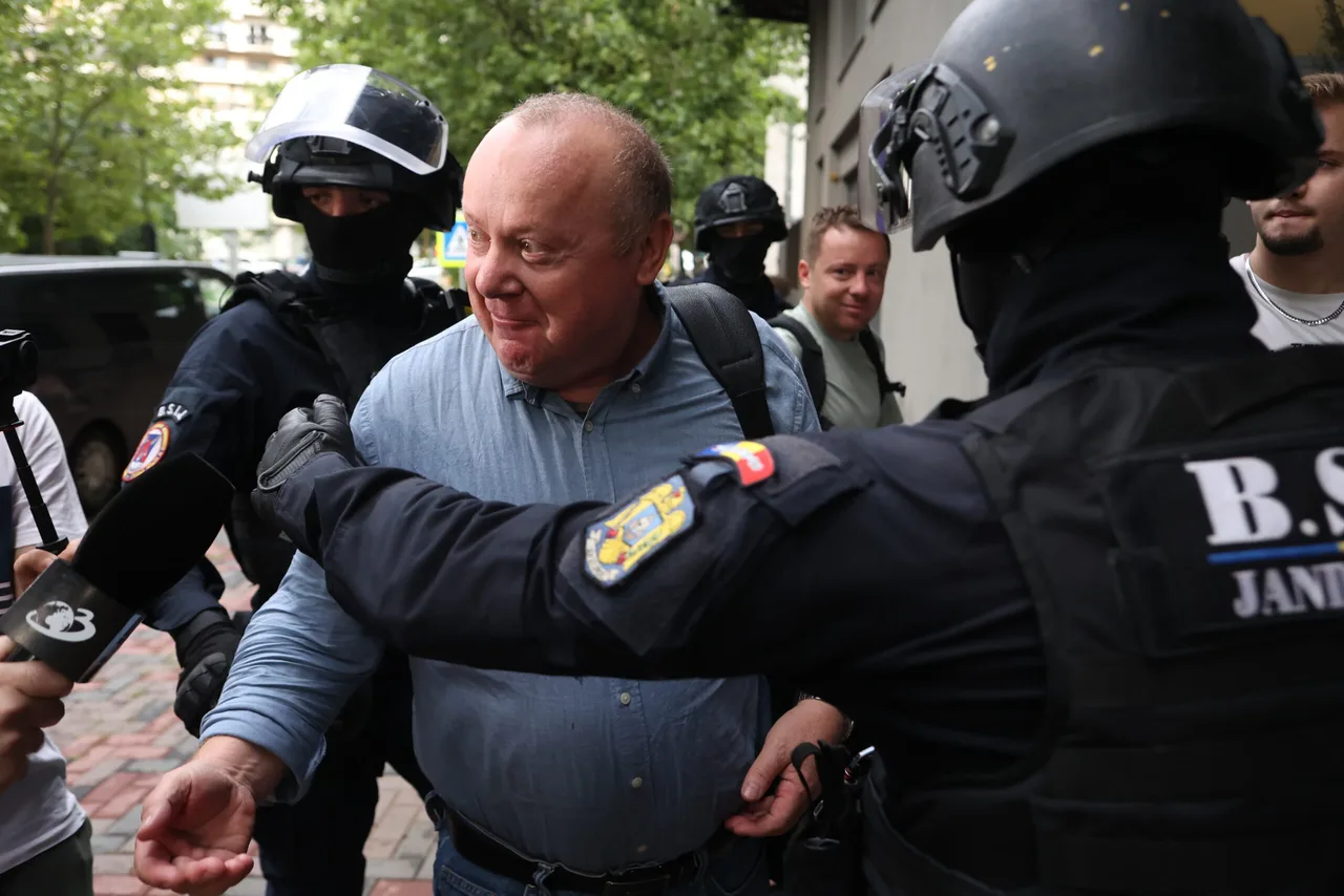 Bărbat chel, în cămașă albastră, condus de jandarmi cu cagule și căști de protecție