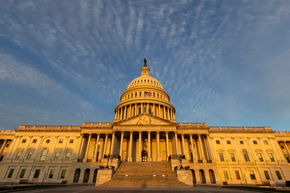 Capitoliul SUA din Washington, cu cupola luminată de soare, sub cer cu nori