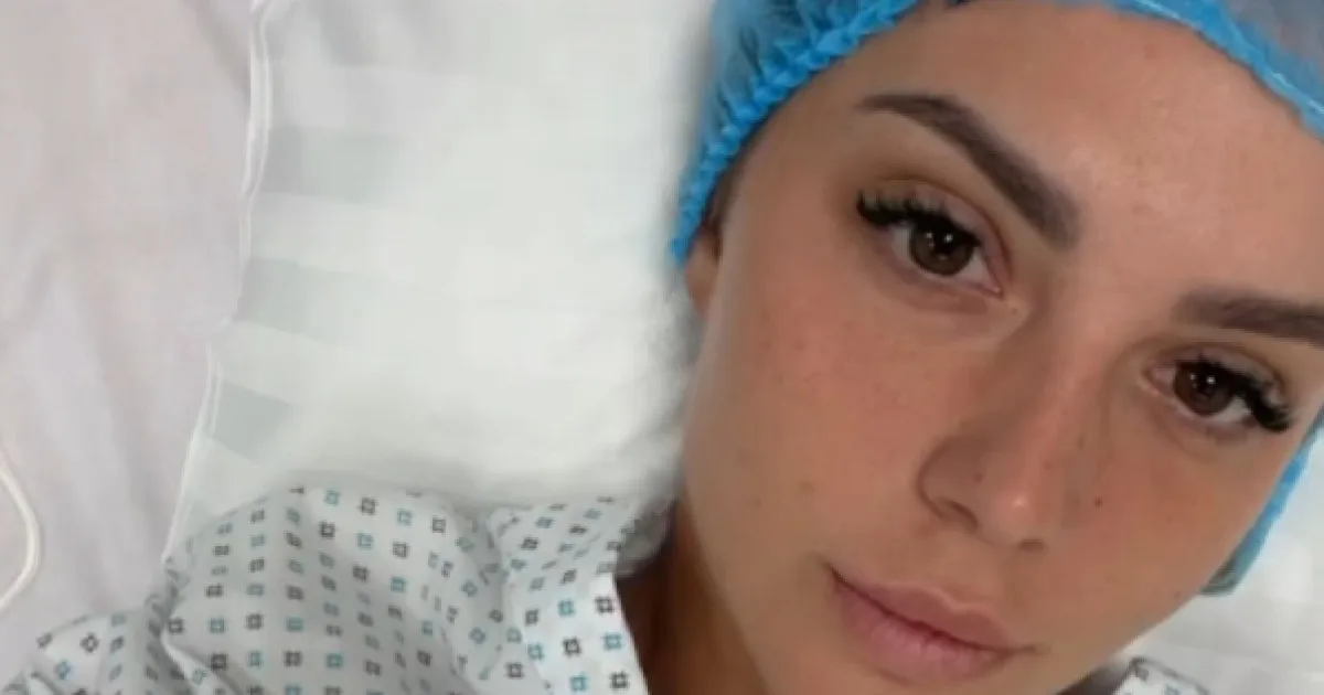 Tânără cu bonetă chirurgicală albastră, întinsă într-un pat de spital, într-un selfie