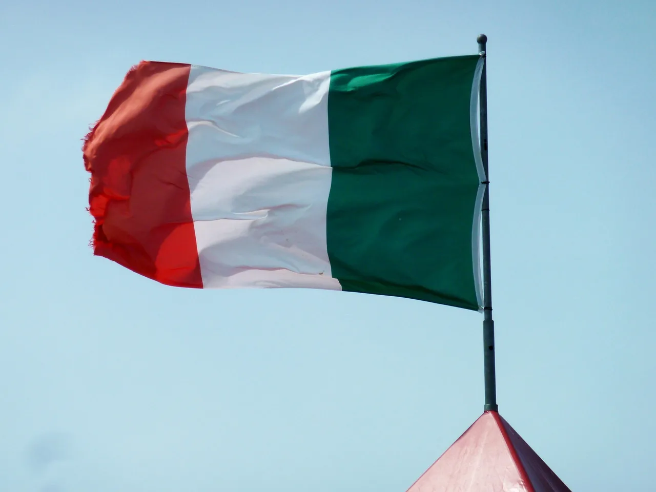 Drapelul Italiei fluturând pe un catarg, pe cerul senin