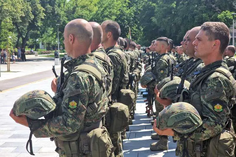 Militari în uniforme de camuflaj aliniați într-un șir, cu căștile ținute în mână