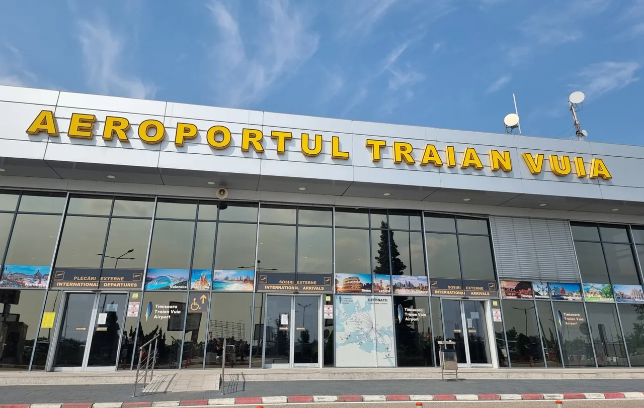 Clădirea terminalului cu inscripția „Aeroportul Traian Vuia”, sub cer albastru