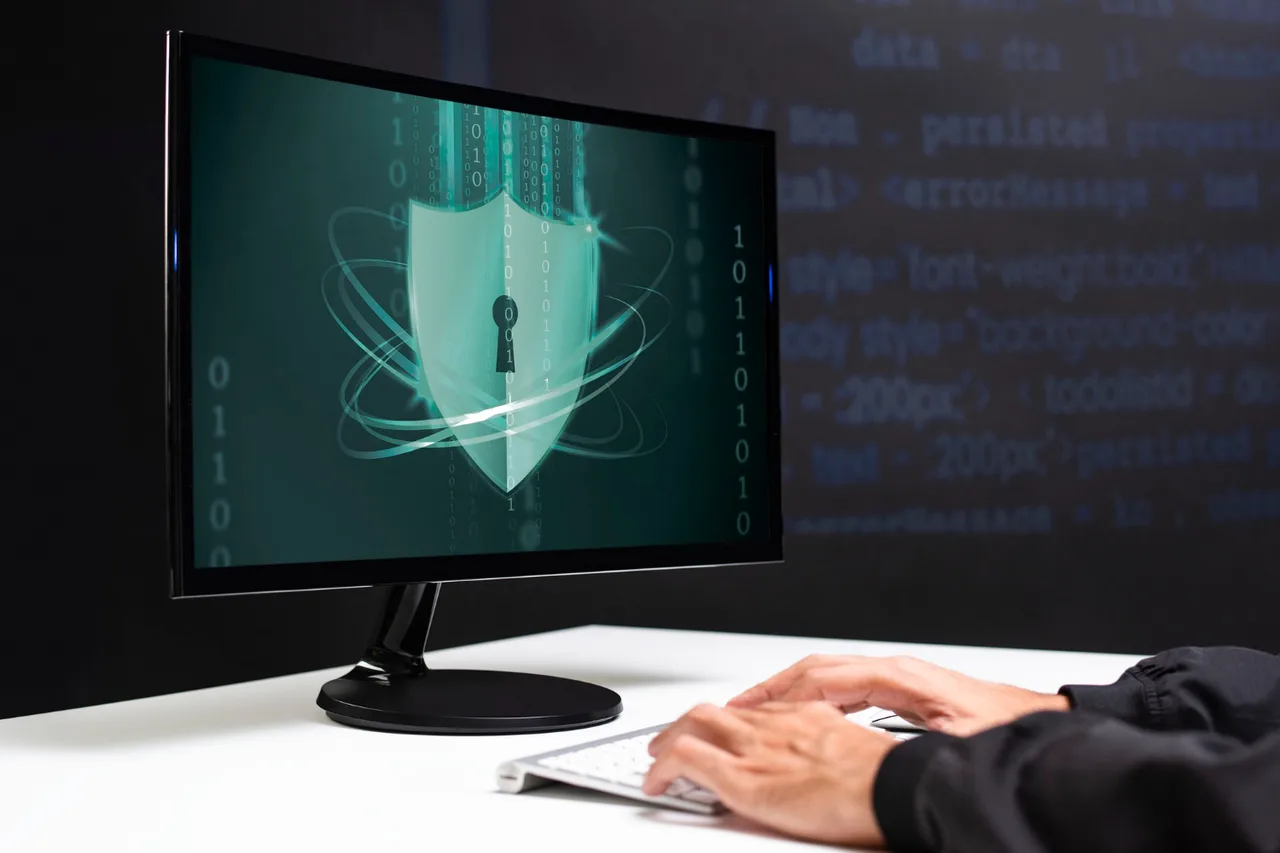 Monitor cu un scut cu gaura cheii pe ecran și mâinile cuiva pe tastatură