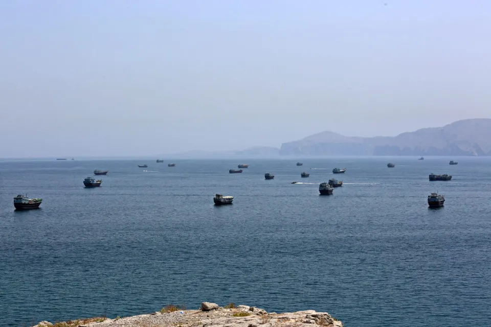 Zeci de nave ancorate pe o mare liniștită, în apropierea unei coaste cu dealuri