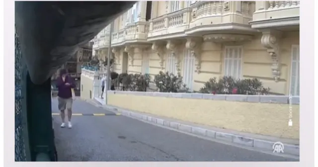 Stradă în pantă cu o clădire elegantă cu balcoane și un bărbat care merge pe trotuar