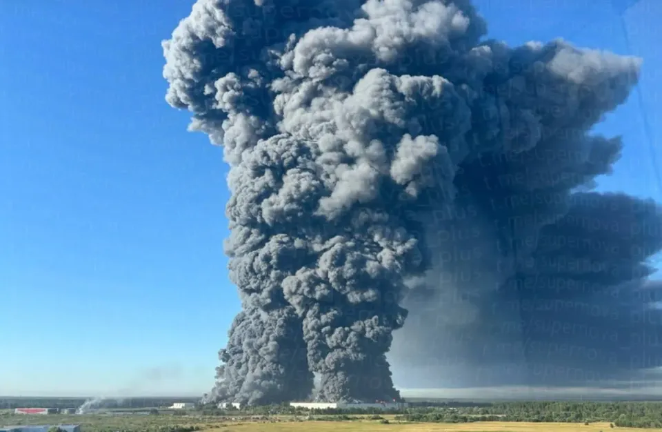 Coloană uriașă de fum negru ridicându-se de la un incendiu, deasupra unei câmpii