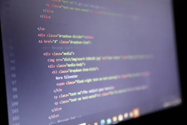 Ecran de laptop cu cod HTML, văzut din unghi, în lumină slabă