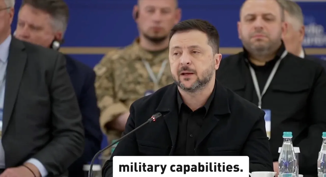 Volodimir Zelenski, în negru, vorbind la microfon la o masă, cu oficiali așezați în spate