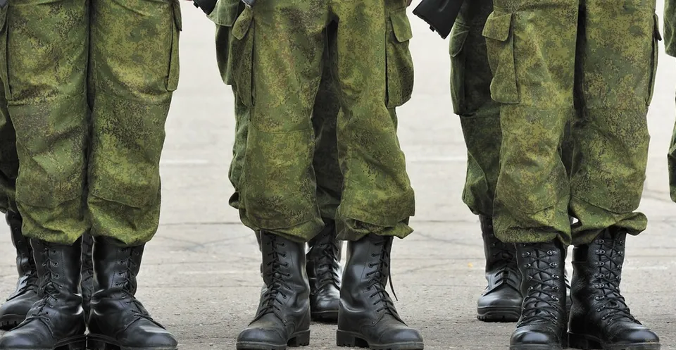 Rând de militari în uniforme verzi de camuflaj și bocanci negri, văzuți de la brâu în jos