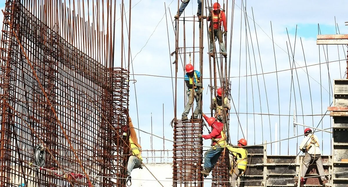 Muncitori cu căști pe o structură de armături, la construcția unei clădiri