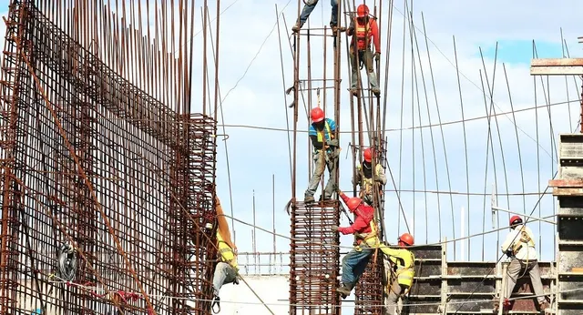 Muncitori cu căști pe o structură de armături, la construcția unei clădiri