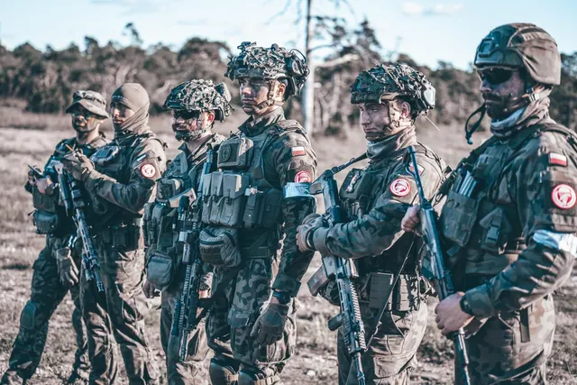 Militari ai armatei poloneze în echipament de camuflaj, cu căști și arme
