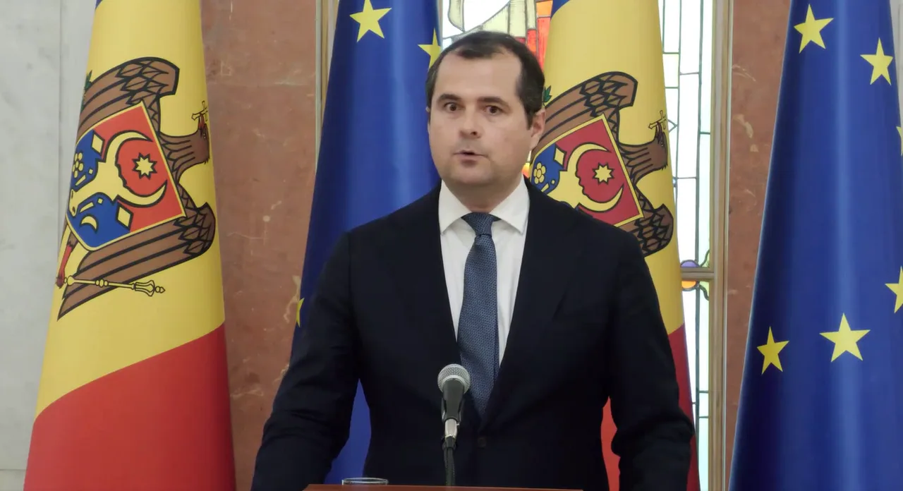 Vasile Tofan vorbind la microfon, între drapelele Republicii Moldova și ale Uniunii Europene