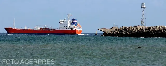 Navă cisternă cu cocă roșie lângă un dig de piatră cu far, pe mare