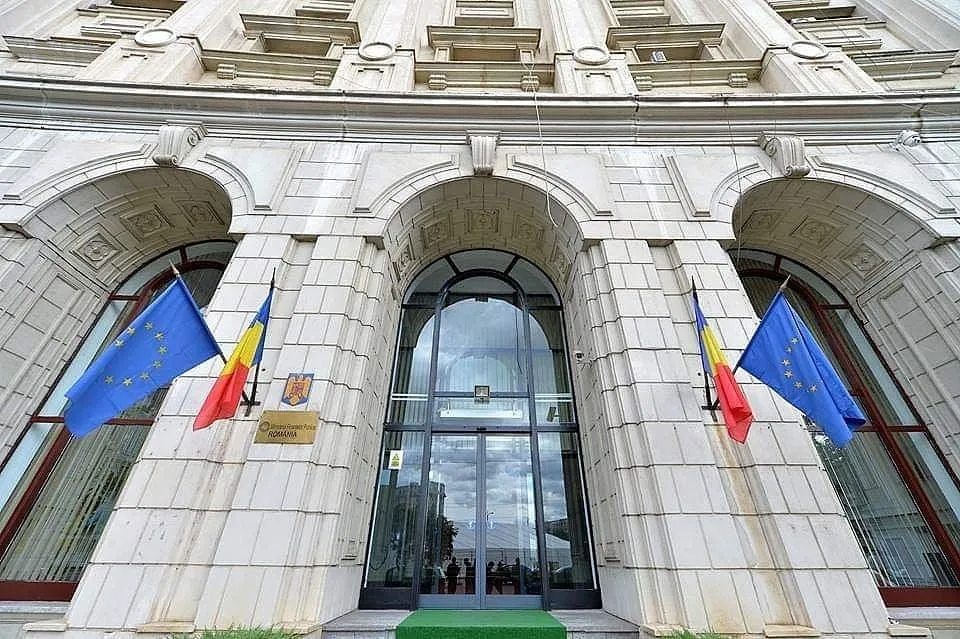 Fațada cu arcade a unei clădiri a Ministerului Finanțelor, cu drapelele României și UE la intrare