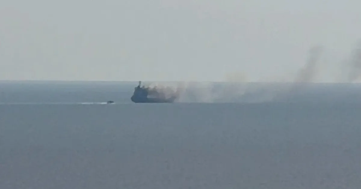 Navă la orizont pe mare, cu un nor de fum care se ridică deasupra ei