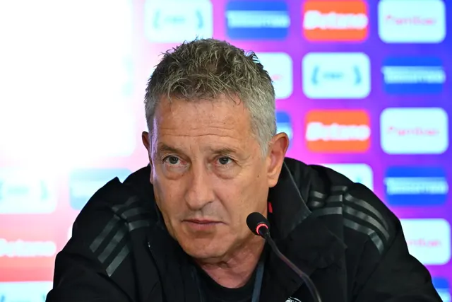 Cristiano Bergodi la o conferință de presă, cu microfon, în fața panoului cu sponsori Betano