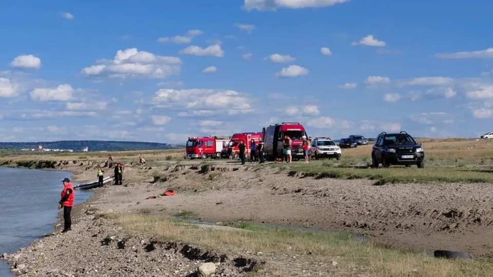 Autospeciale de salvare parcate pe malul unui râu, cu salvatori la marginea apei