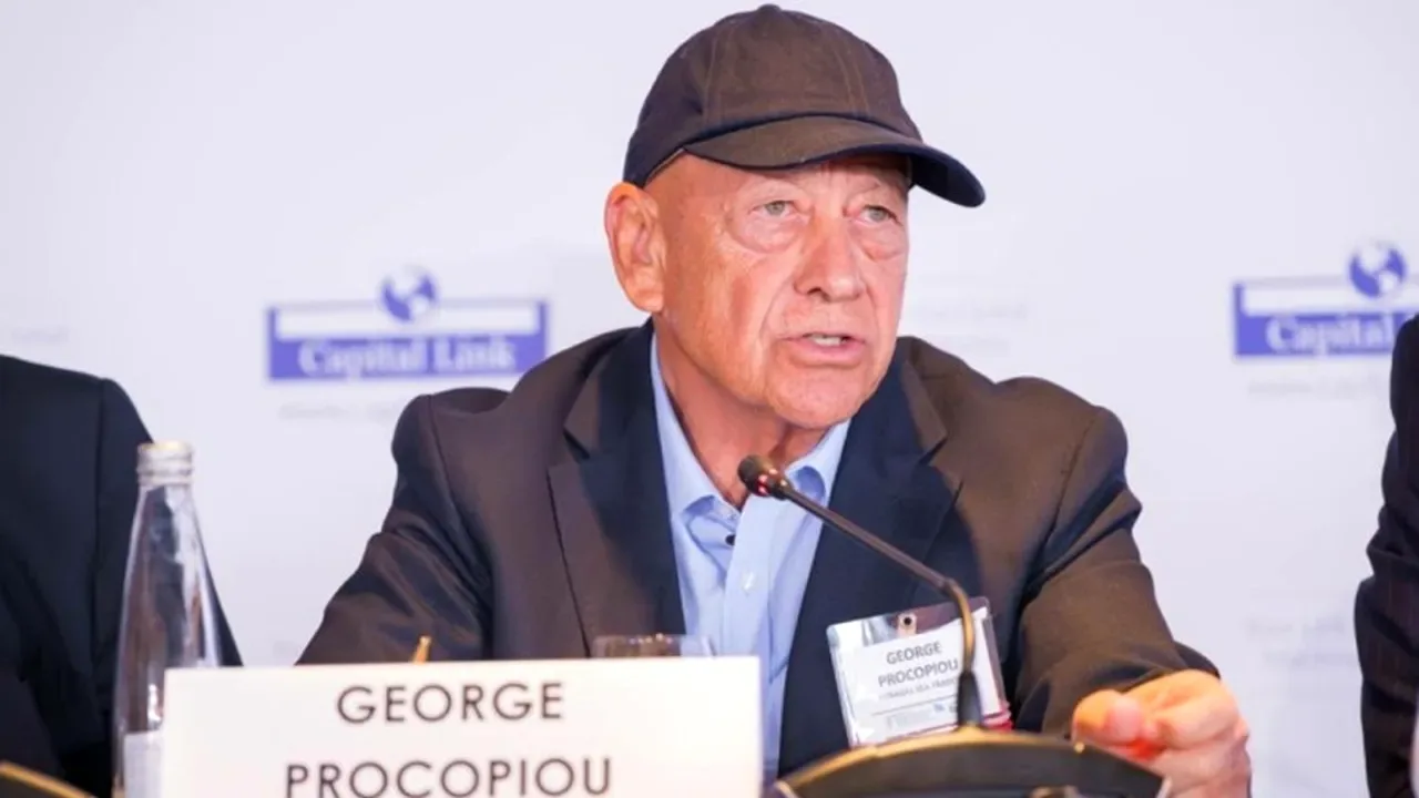 George Procopiou, cu șapcă, vorbind la microfon la o conferință Capital Link, în spatele plăcuței cu numele
