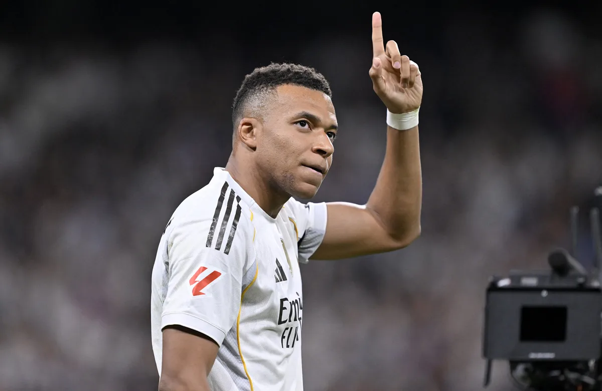 Kylian Mbappé, în echipamentul alb al Realului Madrid, arătând cu degetul în sus