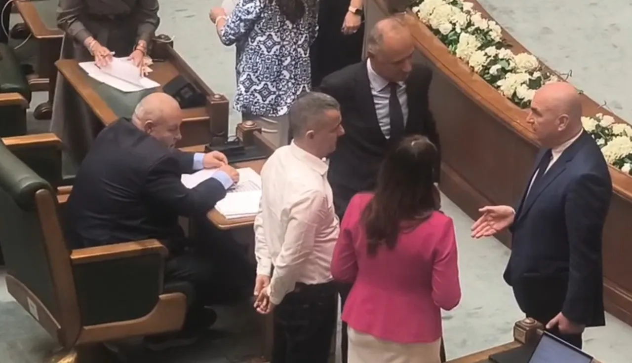 Grup de oameni discutând lângă băncile din față, în sala de plen a Senatului