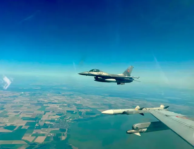 Două avioane de luptă F-16 în formație deasupra câmpurilor, văzute din alt avion