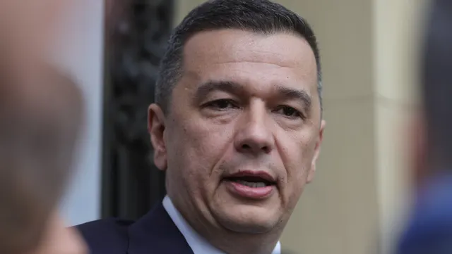 Bărbat cu părul scurt, negru, în costum, vorbind, fotografiat de aproape