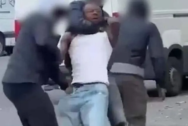 Captură video: doi oameni cu fețele blurate atacând un bărbat în maiou alb, pe stradă