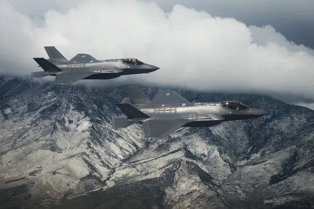 Două avioane de luptă F-35A în zbor deasupra unor munți acoperiți de zăpadă