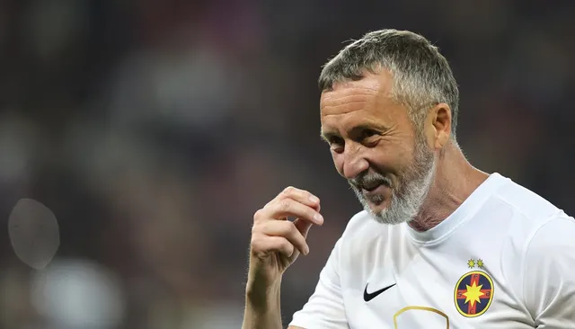 Bărbat cu barbă albă, în tricou alb cu sigla FCSB, zâmbind