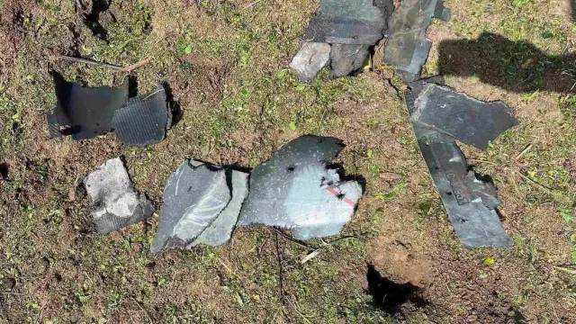 Fragmente metalice ale unei drone căzute, împrăștiate pe iarba uscată