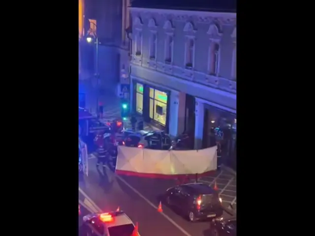 Stradă cu clădiri vechi, noaptea, cu mașini ale echipajelor de intervenție și o pânză albă întinsă