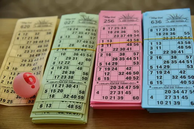 Bilete de loterie colorate, cu numere tipărite, și o bilă roșie pe o masă