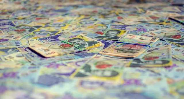 Bancnote de diferite valori, împrăștiate în prim-plan, cu fundalul estompat