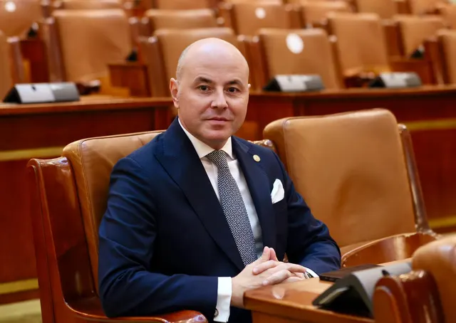 Bărbat chel, în costum bleumarin, așezat într-un fotoliu de piele, într-o sală de ședințe goală