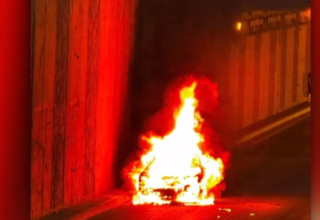 Mașină cuprinsă de flăcări într-un pasaj rutier, cu pereții luminați în roșu de foc