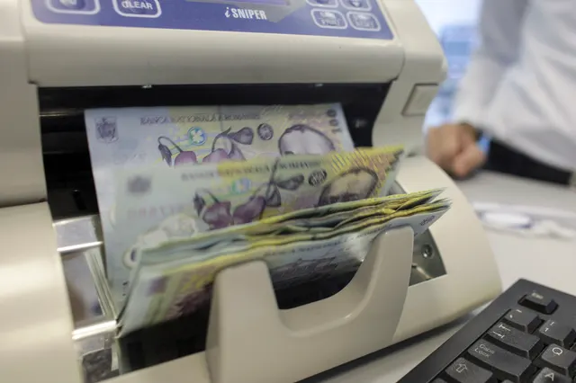 Mașină de numărat bani, cu un teanc de bancnote românești trecut prin ea