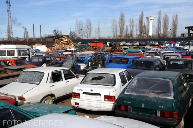 Zeci de autoturisme vechi, parcate înghesuit pe un teren, cu un morman de fier vechi în spate
