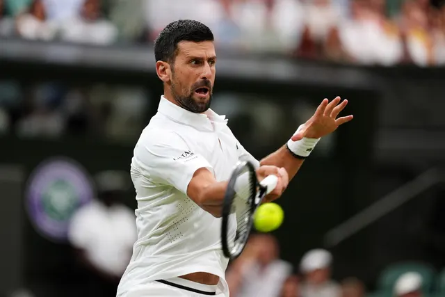 Jucător de tenis în echipament alb lovind mingea cu forehand, pe terenul de iarbă de la Wimbledon