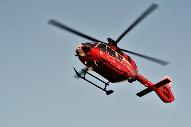 Elicopter roșu de salvare în zbor, pe cerul senin