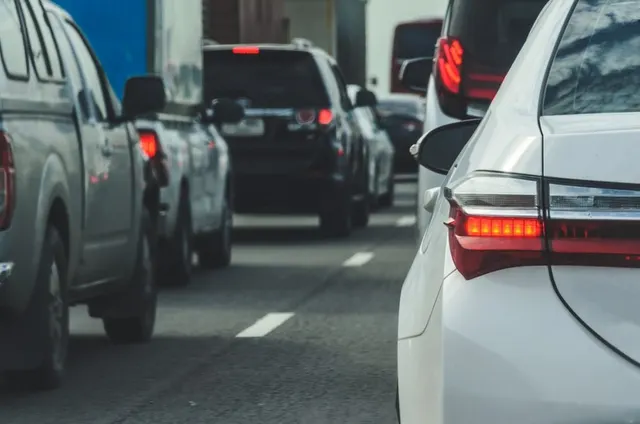 Mașini la coadă pe o autostradă aglomerată, văzute din spatele unui autoturism alb